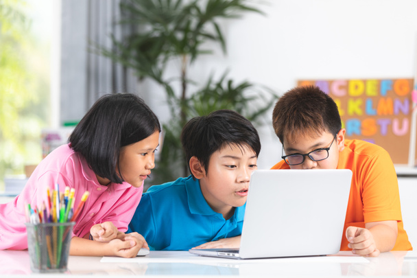 Leuke Aziatische kinderen met behulp van laptop samen met glimlach gezicht. - Foto, afbeelding