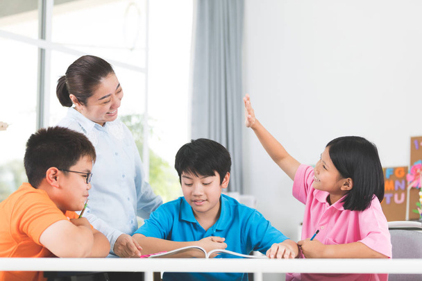 Joven asiático profesor hacer pregunta jóvenes niños en aula
  - Foto, Imagen