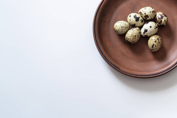 Quail eggs on clay plate on white background. Closeup photo - Foto, afbeelding