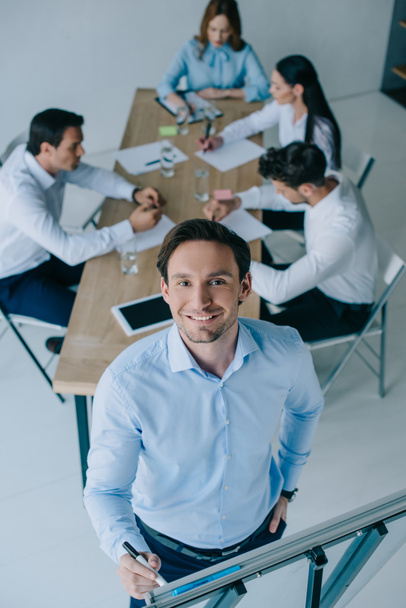 hymyilevän liikemiehen valikoiva keskittyminen valkoiseen hallitukseen ja työpaikalla työskenteleviin työtovereihin
 - Valokuva, kuva
