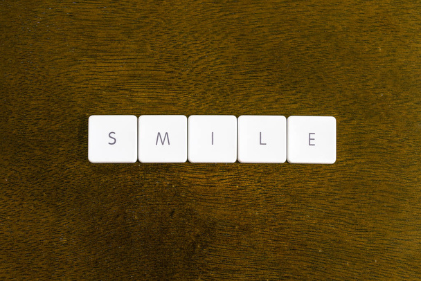 Glimlach woord geschreven op plastic toetsenbord alfabet met donkere achtergrond - Foto, afbeelding