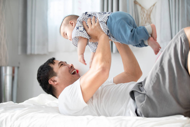 Happy asian family father with baby son playing on bed with smile face. - Foto, Bild