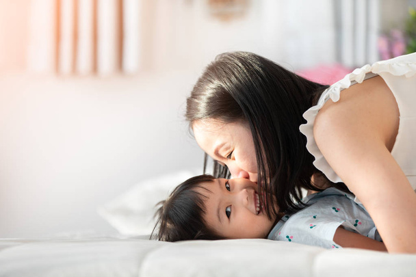 glücklich asiatische Familienmutter mit Tochter spielen auf Bett mit Lächeln Gesicht. - Foto, Bild