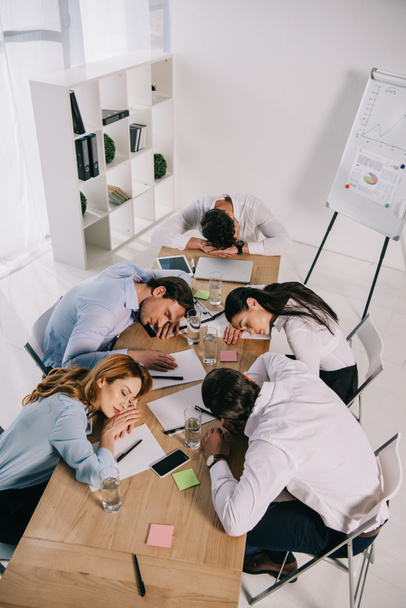 visão de alto ângulo de colegas de negócios cansados dormindo no local de trabalho no escritório
 - Foto, Imagem