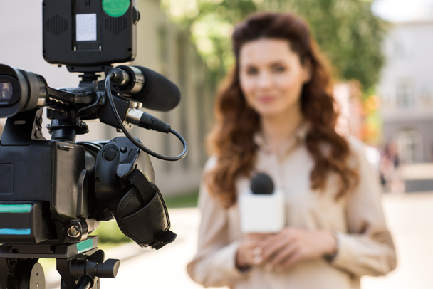 Selektywny fokus dziennikarza z mikrofonem stoi przed cyfrowej kamery wideo - Zdjęcie, obraz