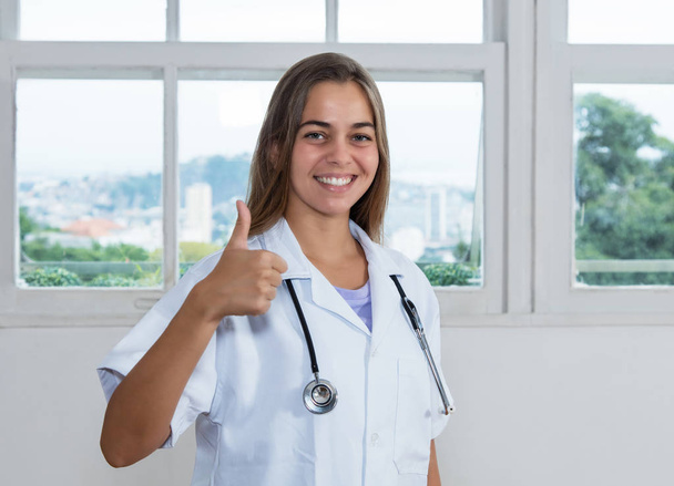 Laughing caucasian female doctor showing thumb up at work at hospital - Fotografie, Obrázek