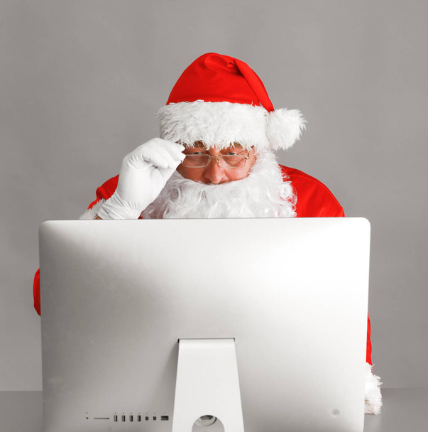 Santa Claus reading children letters and writing responses to them using laptop . - Fotografie, Obrázek