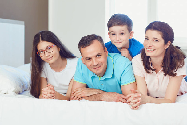 Portrait of happy family lying in bedroom - Фото, зображення
