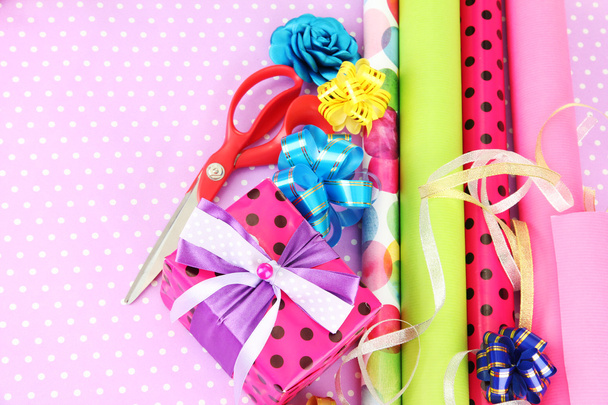 Rolls of Christmas wrapping paper with ribbons, bows on color background - Фото, изображение