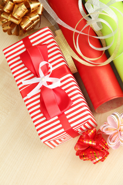 Rolls of Christmas wrapping paper with ribbons, bows on wooden background - Фото, зображення