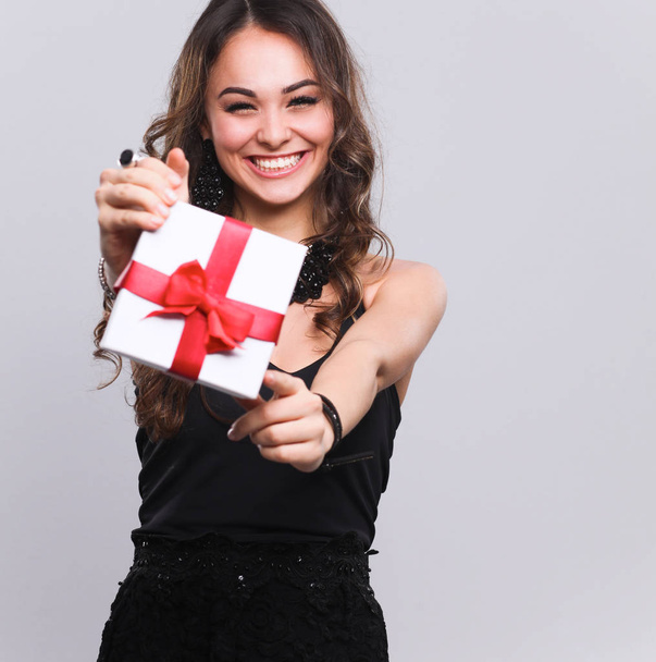Young woman happy smile hold gift box in hands, isolated over grey background - Foto, Imagen