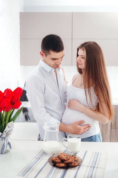 Portrait of a happy pregnant woman with her husband in the kitchen - Photo, image