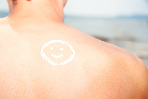 Lotion man with sunscreen smiley above sea background - Photo, Image