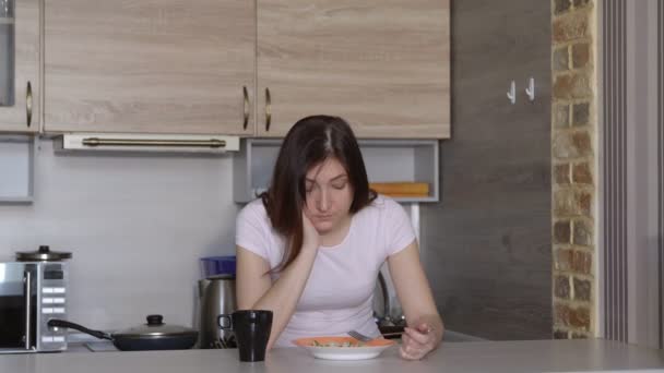 Νεαρή γυναίκα, ύπνος, τρώει στο τραπέζι στην κουζίνα - Πλάνα, βίντεο