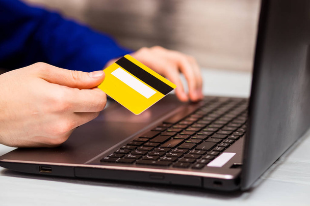 Mann hält Kreditkarte in der Hand und gibt Sicherheitscode über Laptop-Tastatur zu Hause ein. Technologie-, Bank-, Wohn-, Lifestyle- und Online-Shopping-Konzept - Foto, Bild