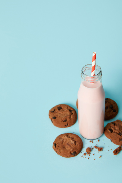 closeup view of chocolate cookies and milkshake in bottle with drinking straw on blue background  - Φωτογραφία, εικόνα