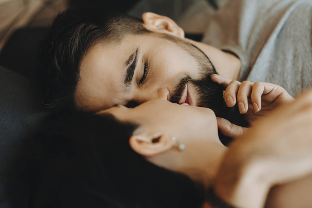 Γενειοφόρος άνδρας όμορφη φιλί σύζυγό του τοποθέτηση στο κρεβάτι. - Φωτογραφία, εικόνα