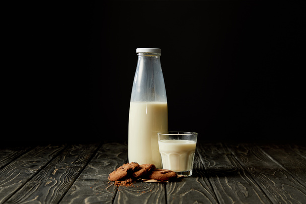 chocolate cookies, milk in bottle and glass on black background  - Photo, Image