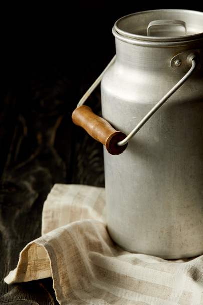 closeup view of milk in aluminium can on sackcloth on black background  - Valokuva, kuva