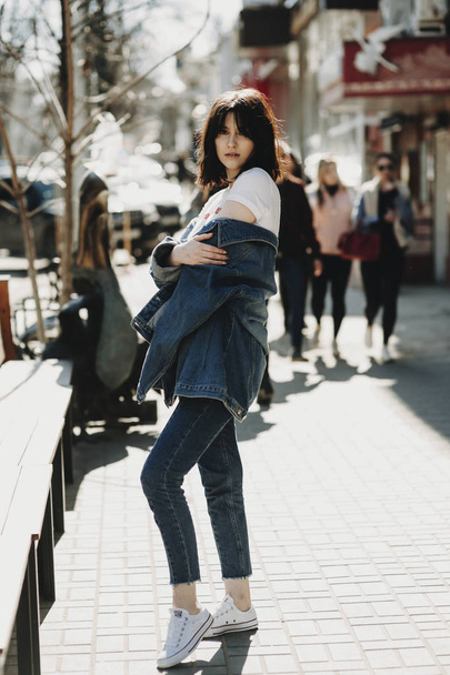 Volledige lengte portret van mooie jonge mode blogger op zoek naar camera, in de straat. - Foto, afbeelding