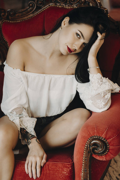 Portret of sensual young girl with red lips, sitting on the chair . - Foto, Imagem