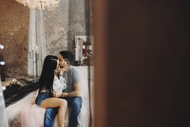 Adulte couple caucasien rester sur le lit et embrasser dans une chambre confortable
. - Photo, image