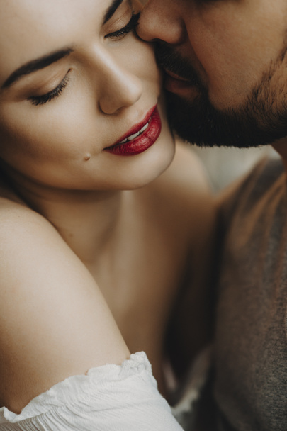 Gros plan portrait d'un beau couple caucasien où l'homme barbu essaie d'embrasser sa femme gaie avec des lèvres rouges
. - Photo, image