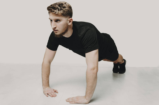 Young blonde man doing push ups in a studio with white background. - Photo, Image
