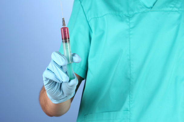 Doctor with syringe on blue background - Foto, afbeelding
