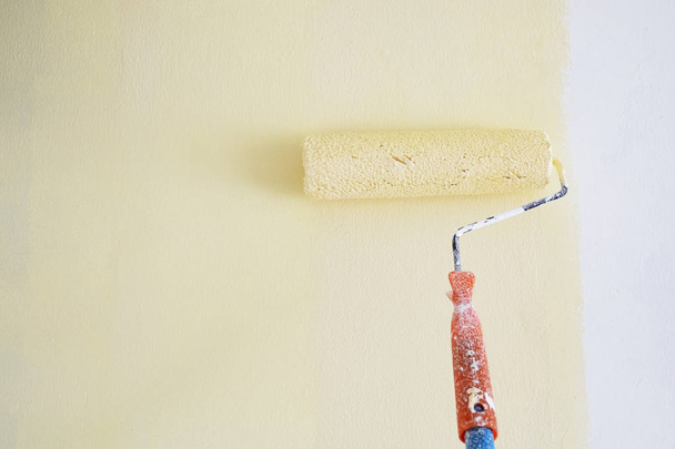 Rulo boya fırçası ışık sarı izole beyaz duvar boyama. - Fotoğraf, Görsel