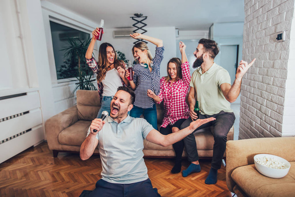 Grupo de jovens amigos jogando karaoke em casa
 - Foto, Imagem