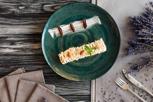 вид зверху солодкий смачний десерт з мигдалем і м'ятою на тарілці на дерев'яному столі
  - Фото, зображення
