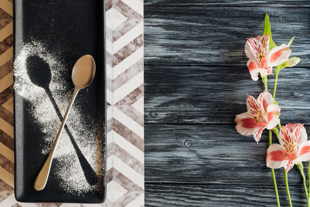 top view of spoon with powder ready for dessert and beautiful flowers on wooden table - Photo, Image