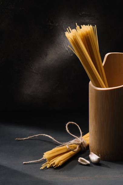 raw spaghetti with garlic on black surface - Foto, afbeelding