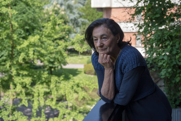 Seniorin steht auf dem Balkon ihres Hauses - Foto, Bild