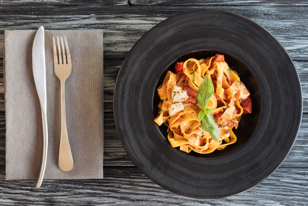 vista superior de la deliciosa pasta italiana y tenedor con cuchillo en mesa de madera
 - Foto, imagen
