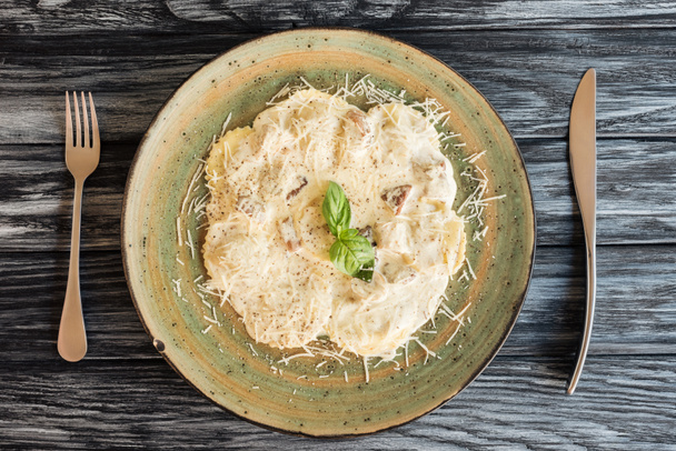 delicious italian ravioli with ricotta cheese on plate and fork with knife on wooden table   - Photo, Image