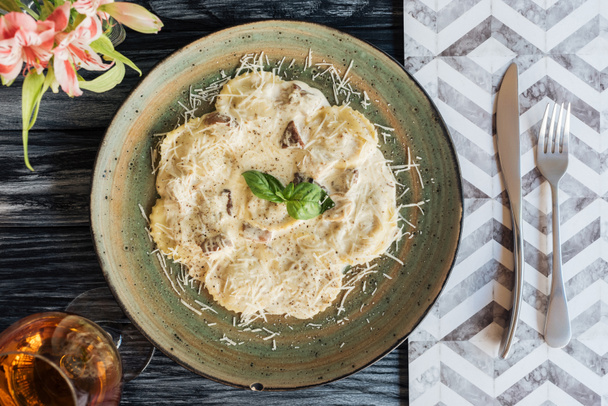 vista superior de ravioles italianos gourmet en plato y tenedor con cuchillo en mesa de madera
 - Foto, imagen