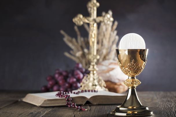 First holy communion theme. The Cross, Holy Bible, rosary and golden chalice. Bread and grapes  symbols of Christianity. - Photo, Image