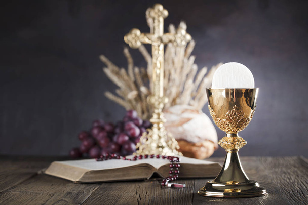 Eerste heilige communie thema. Het Kruis, Heilige Bijbel, rozenkrans en gouden kelk. Brood en druiven symbolen van het christendom. - Foto, afbeelding
