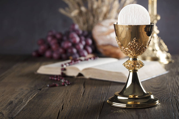 First holy communion theme. The Cross, Holy Bible, rosary and golden chalice. Bread and grapes  symbols of Christianity. - Foto, immagini
