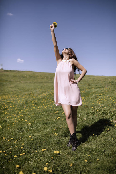 A beautiful woman in her dress enjoys a glade of mountain flowers - Zdjęcie, obraz