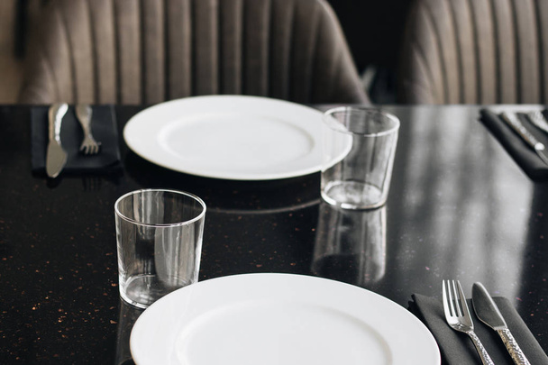 białe talerze, szklanki i naczynia na czarny stół, elegancka zastawa stołowa  - Zdjęcie, obraz