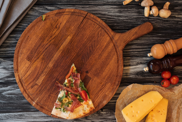 Blick von oben auf eine einzelne Scheibe leckere Pizza auf einem Holzschneidebrett - Foto, Bild