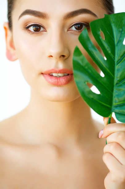 Skin Care. Beautiful Girl with Green Leaves. Beauty Treatment. Cosmetology. Beauty Spa Salon - 写真・画像