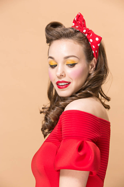 Beautiful young woman with pinup make-up and hairstyle. Studio shot on pastel background - Фото, изображение