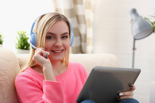 Mladá krásná blonďatá žena sedět na pohovce v obývacím pokoji držení tabletu v náručí poslouchat hudbu sunny - Fotografie, Obrázek