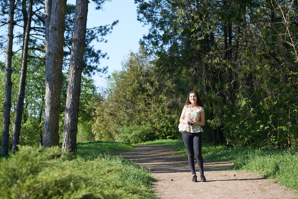 молодая девушка, гуляющая в весеннем лесу с камерой и фотографирующая
 - Фото, изображение