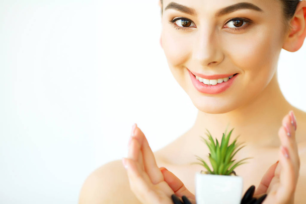 Hautpflege. Frau mit klarer Haut, die grüne Aloe Vera Pflanze hält. Schönheitsbehandlung. Kosmetologie. Schönheitssalon - Foto, Bild