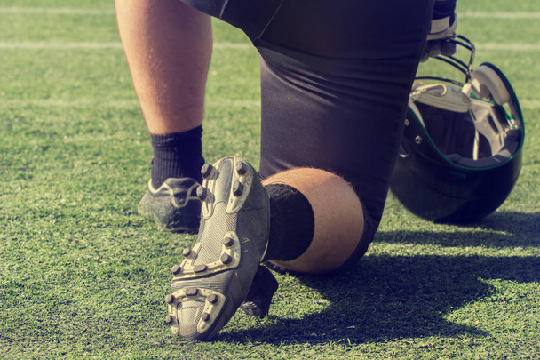 Hráč amerického fotbalu, stojící na jednom koleni na zelené louce - Fotografie, Obrázek